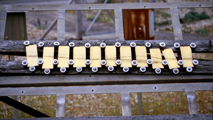 film still: Line on yellow plates: This shot is one of a number in the film where I mixed scratching marks made directly on to unprocessed celluloid and scanned on to my PC, with stills images of the site. In this case the scratch was a longish wavy line, scanned in reverse (dark scratch on light background) &amp; laid over images of the line on the series of yellow plates. The next step was to rub out, on PC using a software package called AURA, the points where the scratches extended beyond the plates.

